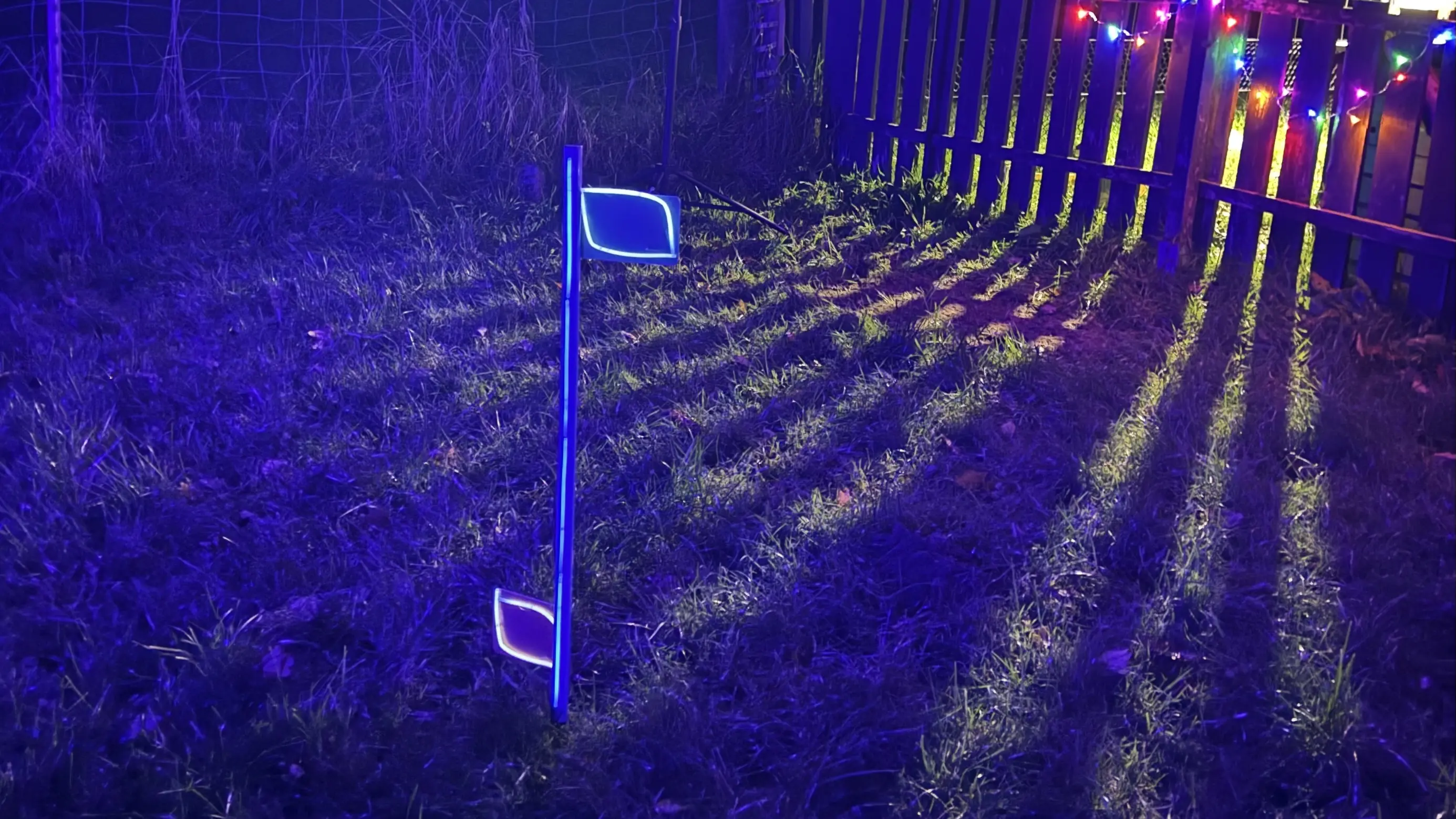 Curvingstange mit Knicklichtern vor einem Zaun mit Lichterkette